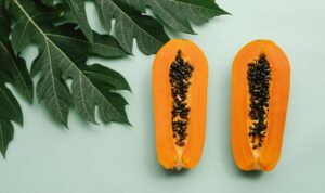 Top view of freshly halved papayas with leafy background, highlighting tropical freshness.